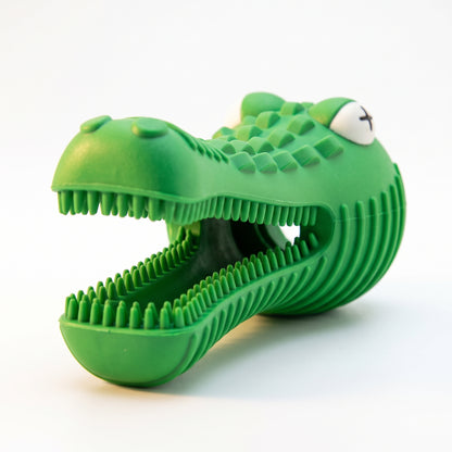 A green alligator-shaped silicone pet toy with an open mouth, textured scales, and a small white eye detail, shown on a plain white background.